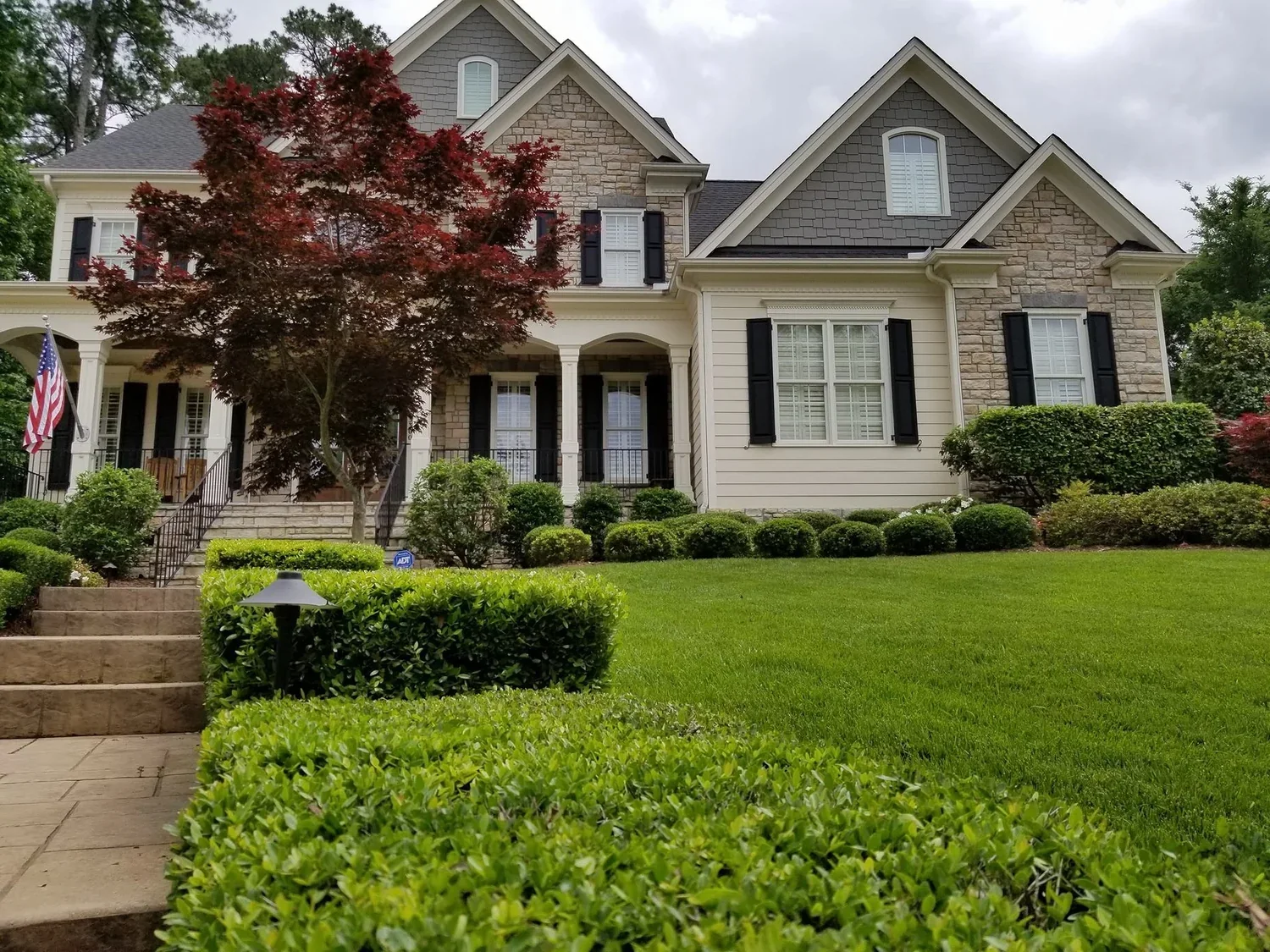 A professionally maintained Raleigh home with a neat lawn, shaped shrubs, and clean landscape beds