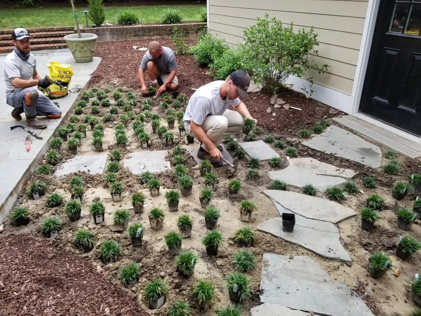 Wake Pro crew members installing a patterned planting bed beside a Raleigh home